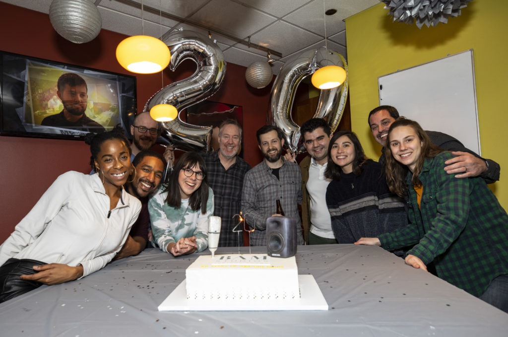 BAM team gathered around anniversary cake